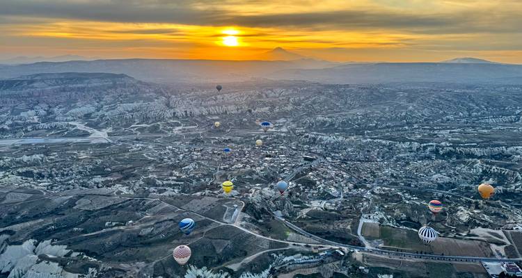 Aerial view of hot air balloons over Cappadocia at dawn.