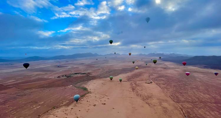Hot air balloons soaring over a vast desert landscape.