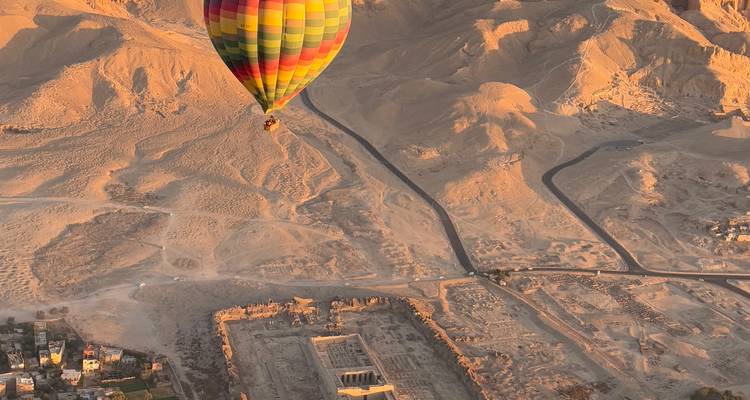 Heteluchtballon boven woestijnlandschappen en oude ruïnes.