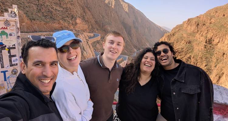Group of friends smiling with a scenic mountainous backdrop.