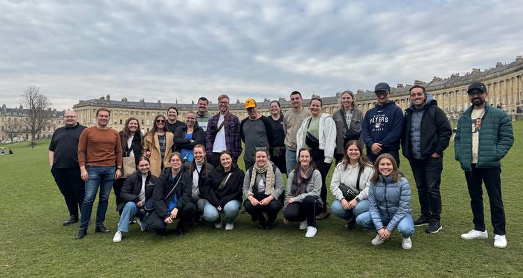Large group of people posing in front of historic buildings.