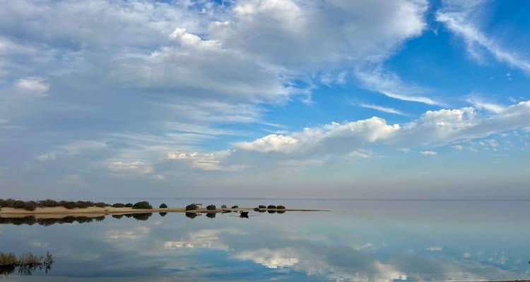 Vista serena de agua reflectante con cielo nublado.