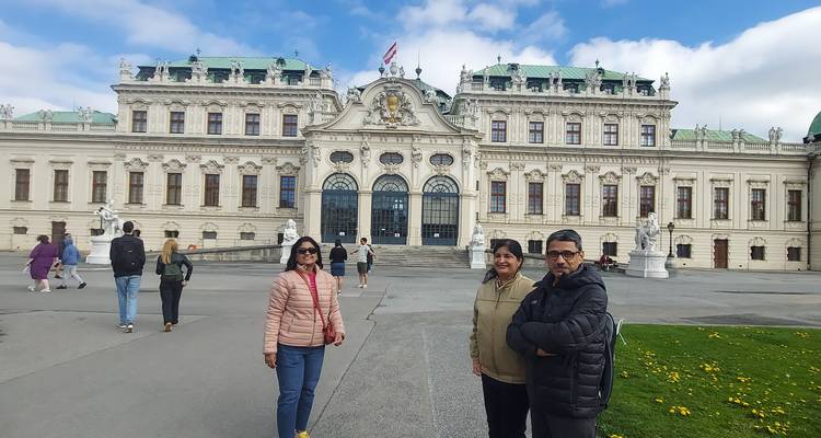 A group of people outside a grand historic palace.