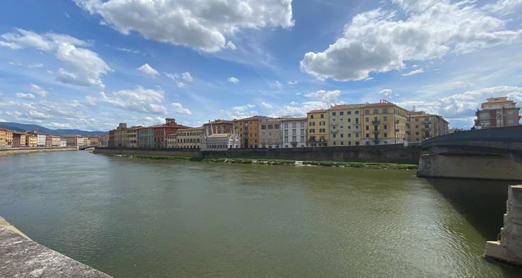 River with colorful buildings under a cloudy sky.