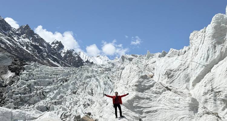 Person with arms raised on a snow-covered glacier.