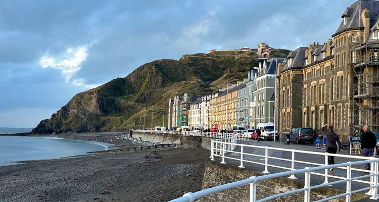 Beachfront view of Aberystwyth with a promenade and colorful buildings.