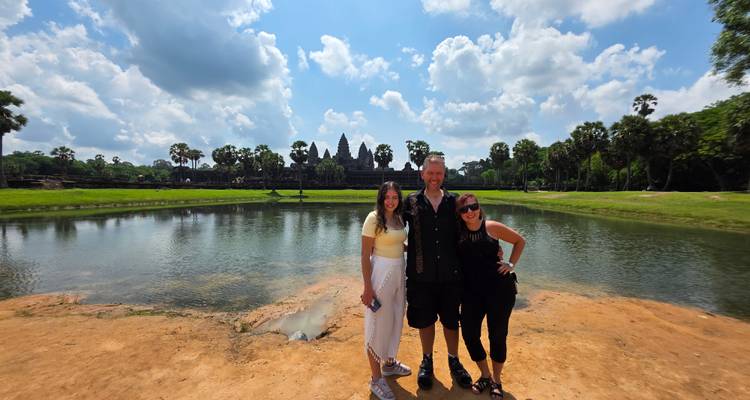 Smiling group posing with Angkor Wat temple in background.