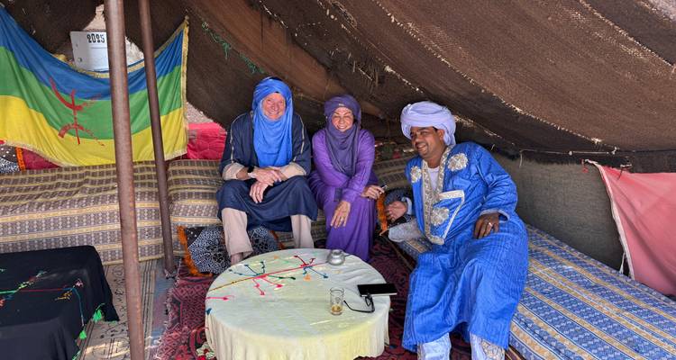 Three people in traditional Berber tent with colorful patterns.