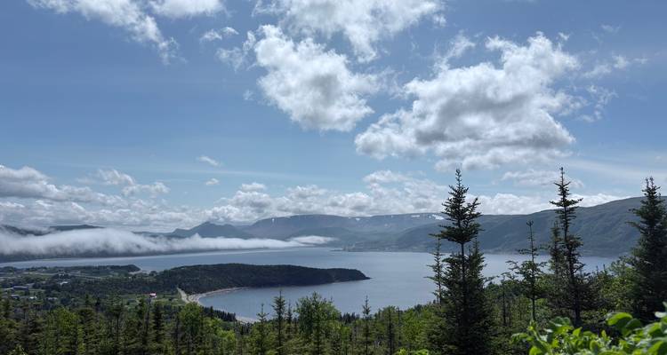 Mountainous landscape with a bay and low clouds.