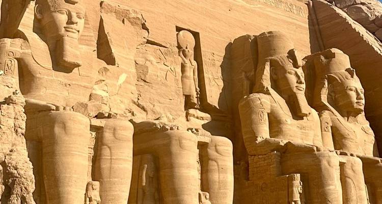 Statues colossales d'Abou Simbel sous une lumière chaleureuse du soleil.