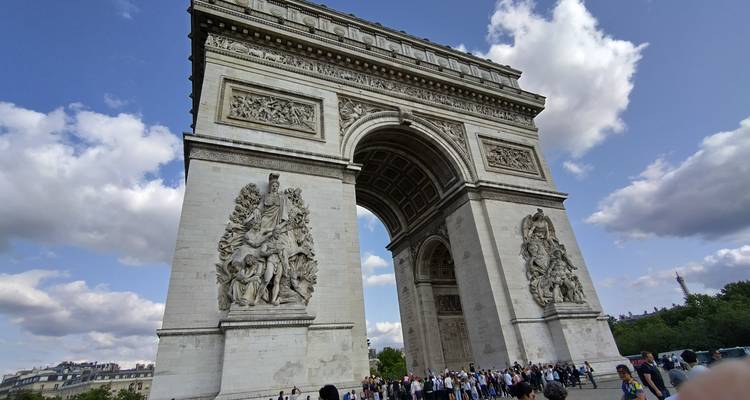 Grand groupe de touristes rassemblé sous l'Arc de Triomphe.