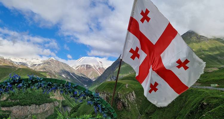 Drapeau de la Géorgie avec des montagnes en arrière-plan.