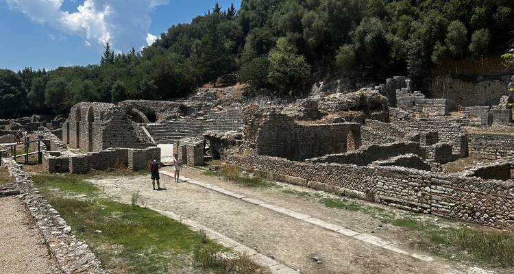 Ruinas antiguas en un área boscosa con personas explorando.