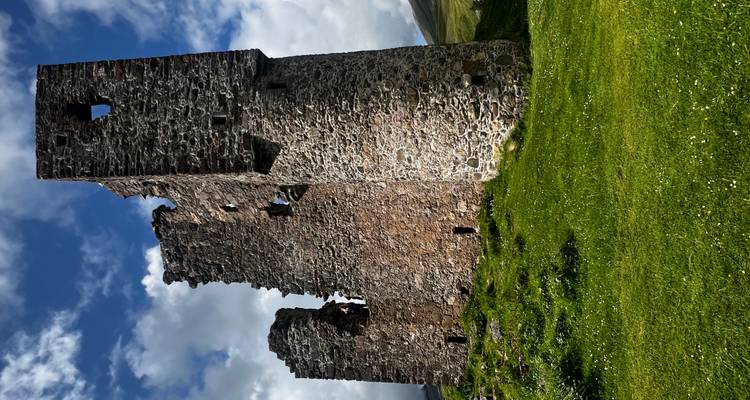Ruines d'une tour de pierre contre un ciel nuageux.