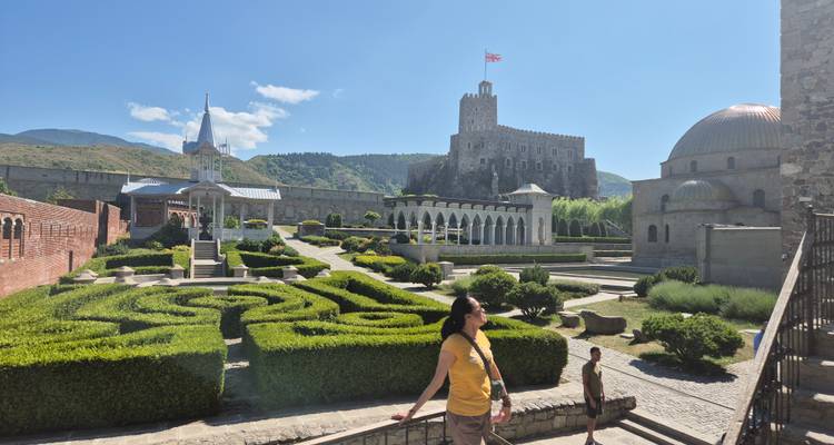 Femme marchant dans un jardin paysager avec un bâtiment historique.