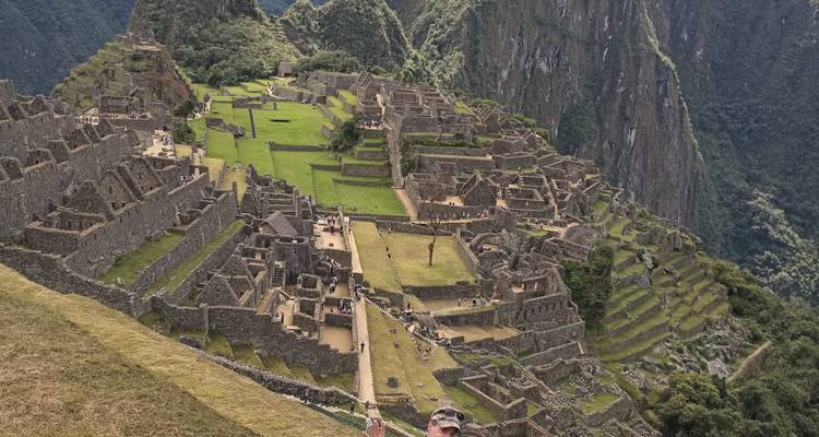 Panoramic view of Machu Picchu with a person in the foreground.