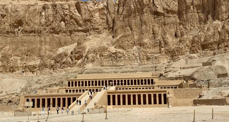 Complejo de templos construido en un acantilado con personas explorando.