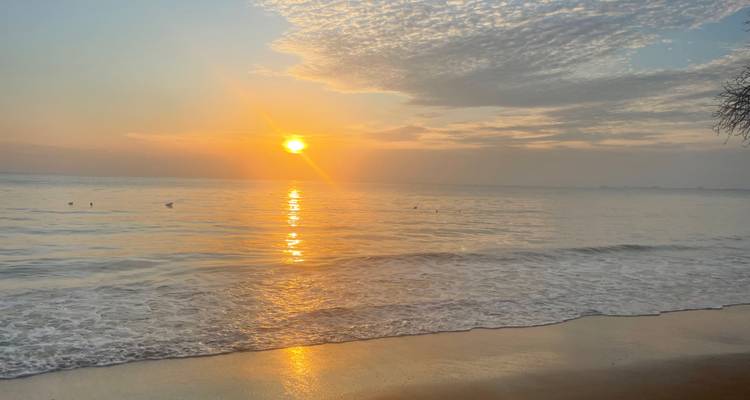 Sunset view over the ocean with waves and a soft glow.