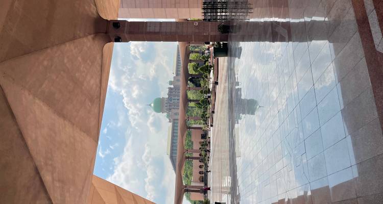 Distant view of a green-domed building through an archway.