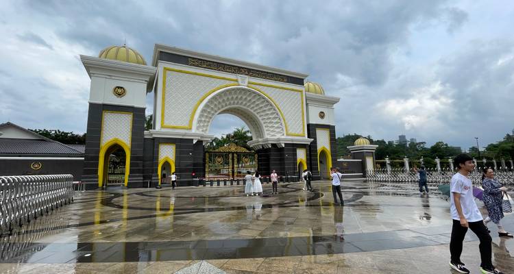 Ornate gate with golden domes and people admiring the architecture.
