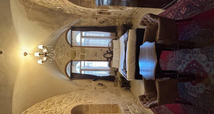 Ancienne salle en pierre avec fenêtres cintrées et mobilier vintage.