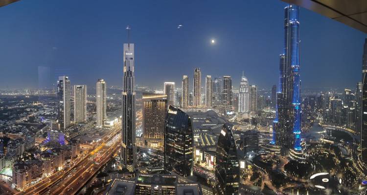 Vue nocturne panoramique d'une ville avec des gratte-ciel illuminés.