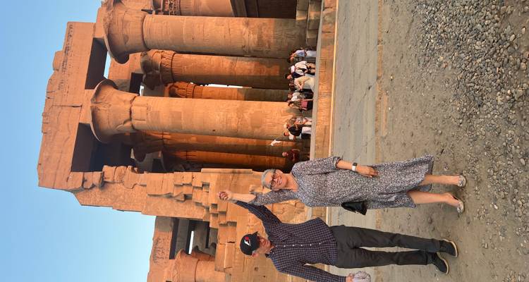 Couple se tenant la main devant un grand temple avec des colonnes.