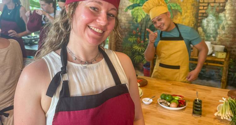 Person in a cooking class with a chef showing ingredients.