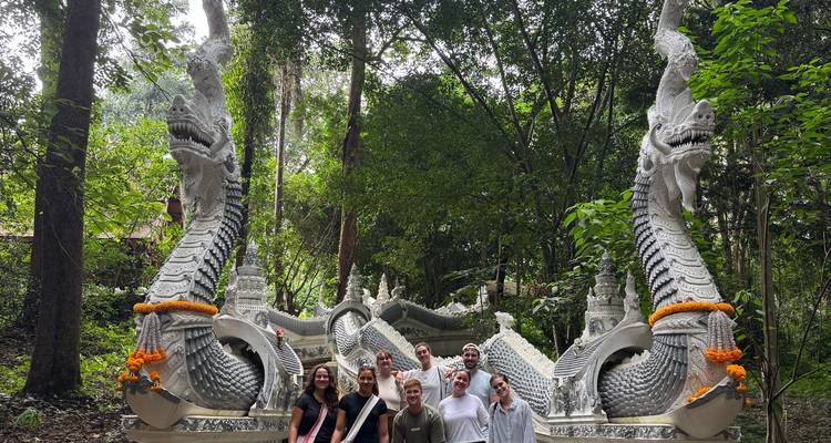 Groupe de personnes posant devant une sculpture de grandes créatures serpentines.
