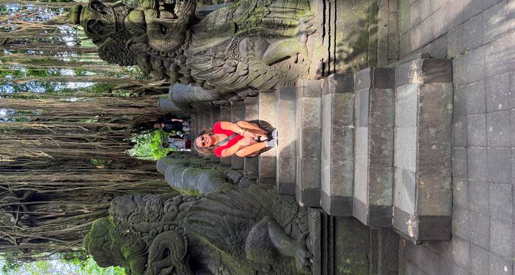 Person sitting on stone steps guarded by statues.