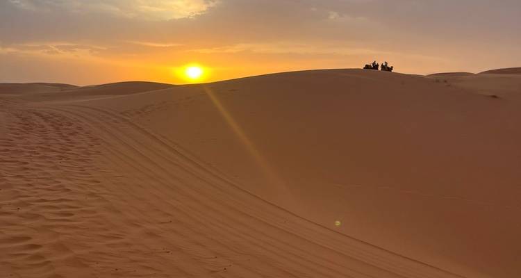Coucher de soleil sur les dunes de sable avec des traces.