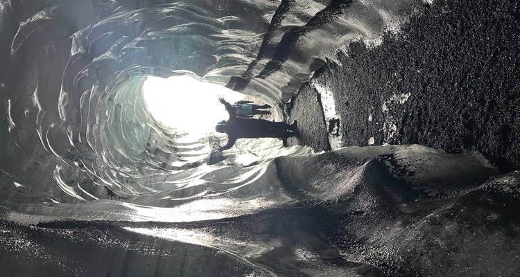 Menschen erkunden eine Eishöhle mit einströmendem Licht.