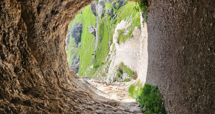 Tunnelöffnung, die eine malerische Landschaft draußen enthüllt.