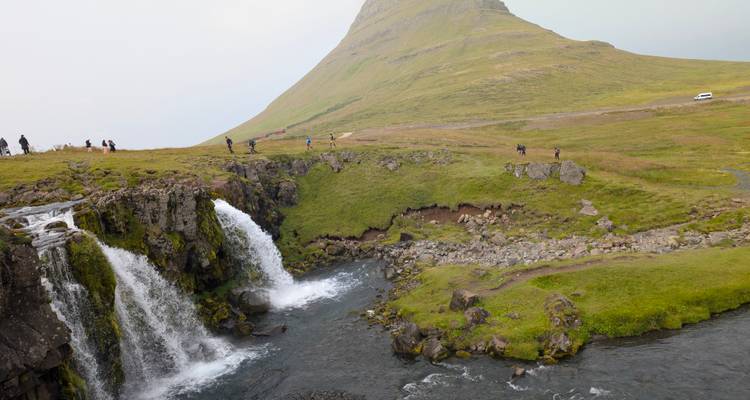 Waterfall flowing with mountain backdrop.