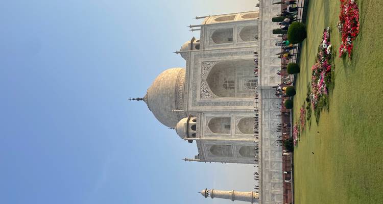 Le Taj Mahal avec des jardins bien entretenus et un ciel bleu dégagé.