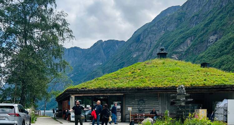 Groupe de personnes près d'un bâtiment au toit recouvert d'herbe entouré de montagnes.