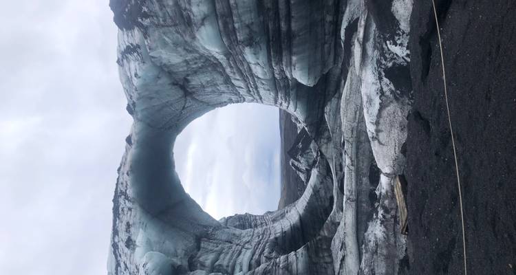 A natural ice formation with a circular tunnel in a glacier.