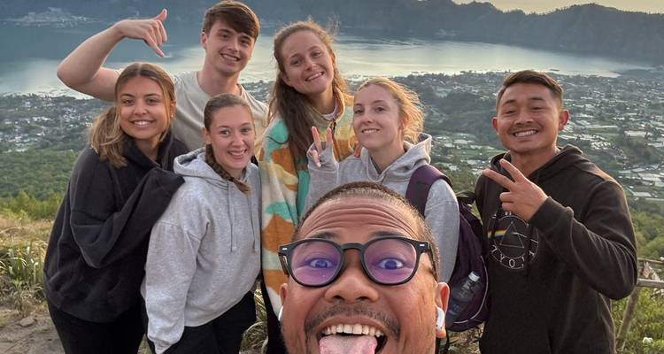 Group selfie with scenic view of a lake and town.