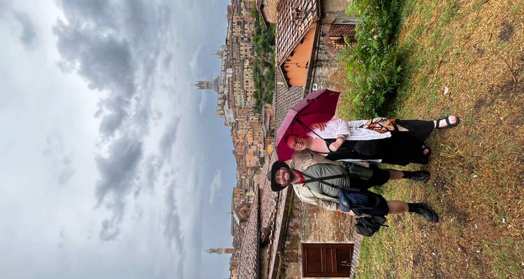 Couple posant avec un parapluie dans une ville pittoresque.