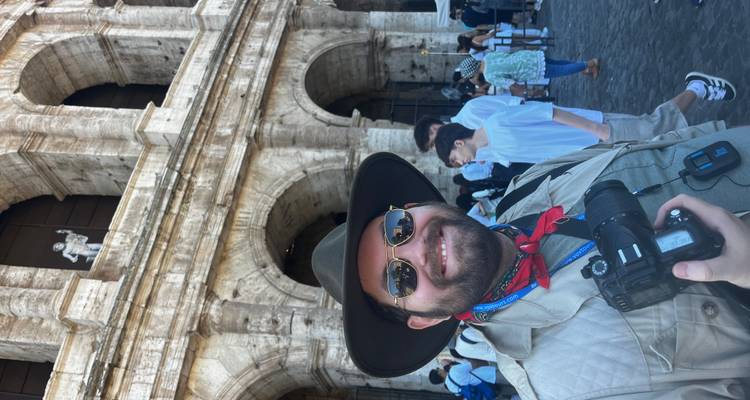 Homme posant devant le Colisée romain.