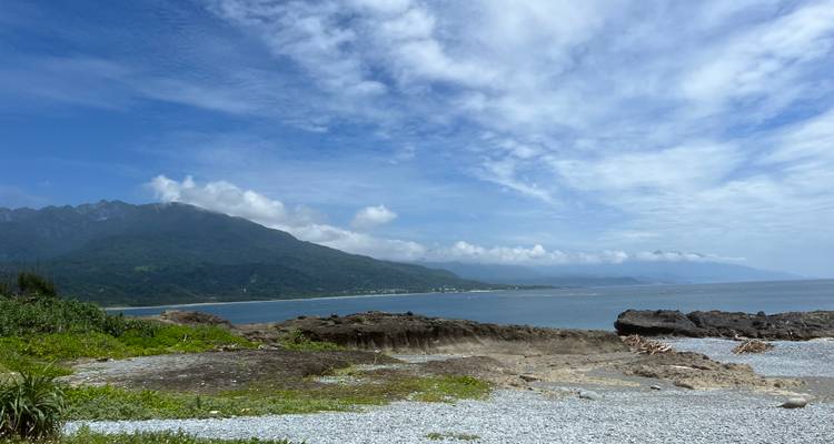 Paysage côtier pittoresque avec des montagnes au loin.