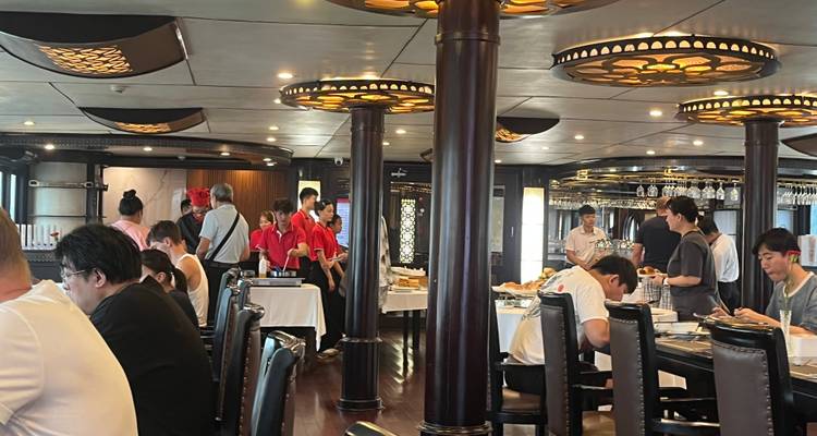 Bustling night market by the water with many illuminated boats.