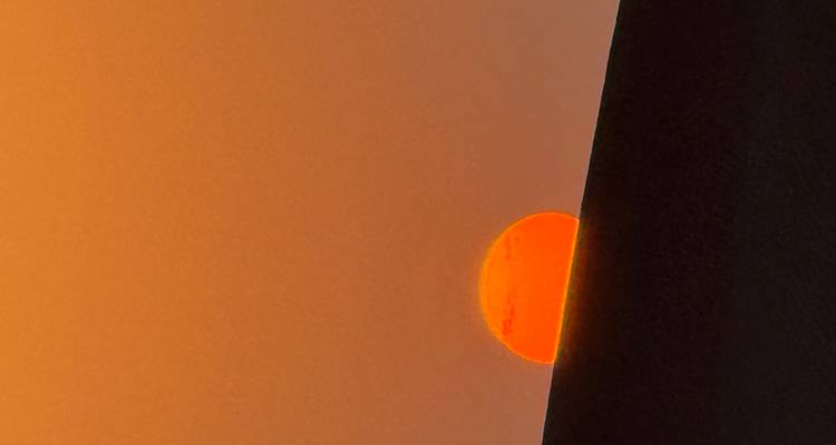 Rote Sonne, die über fernen Hügeln untergeht.