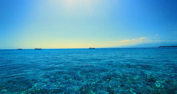 Weiter Ozean mit klarem blauen Wasser und fernen Booten.