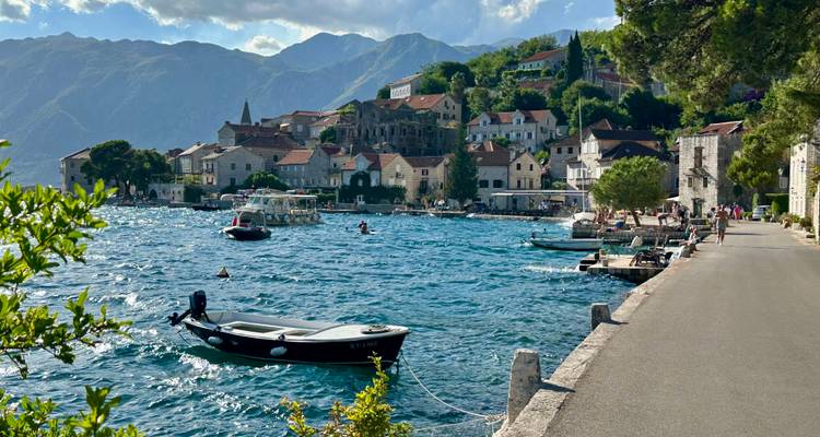 Ville côtière avec des bateaux et des collines luxuriantes en arrière-plan.