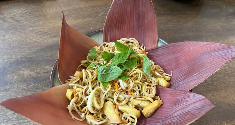 Un plat élégamment présenté avec des nouilles et des herbes sur la table.