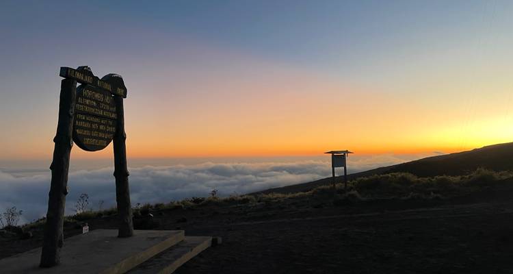 Vue du coucher de soleil depuis le Kilimandjaro avec des nuages pittoresques et de la signalisation.