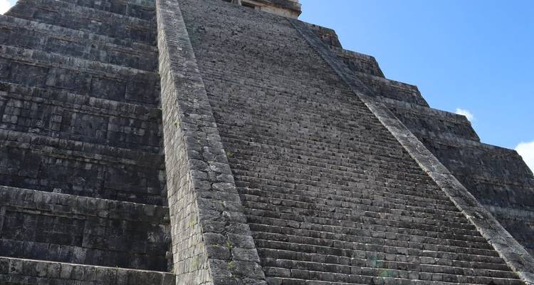 Una pirámide maya con escalones empinados contra el cielo.