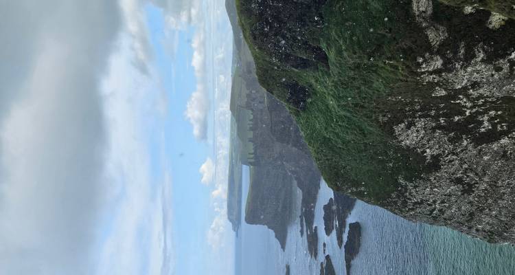 Côte spectaculaire avec falaises et océan sous un ciel nuageux.
