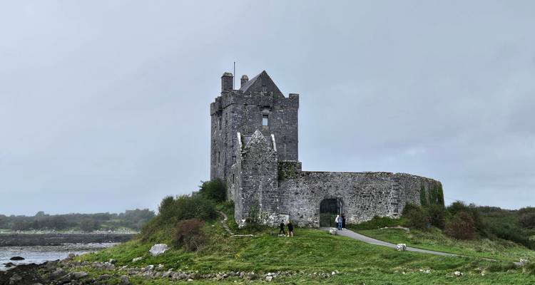 Vieux château de pierre sur une colline herbeuse avec des murs d'enceinte.